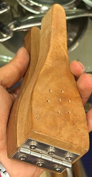 An artisan's hands sanding a carved wooden form